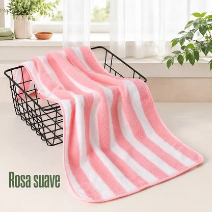 Toalha de rosto rosa e branca em algodão felpudo, macia e compacta, junto ao lavatório.